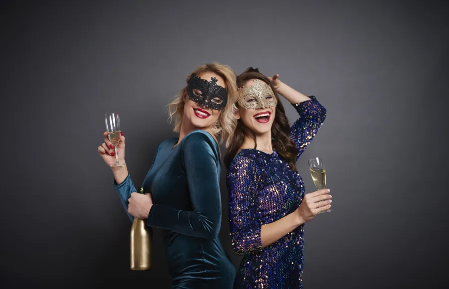 Women masks drinking champagne studio shot